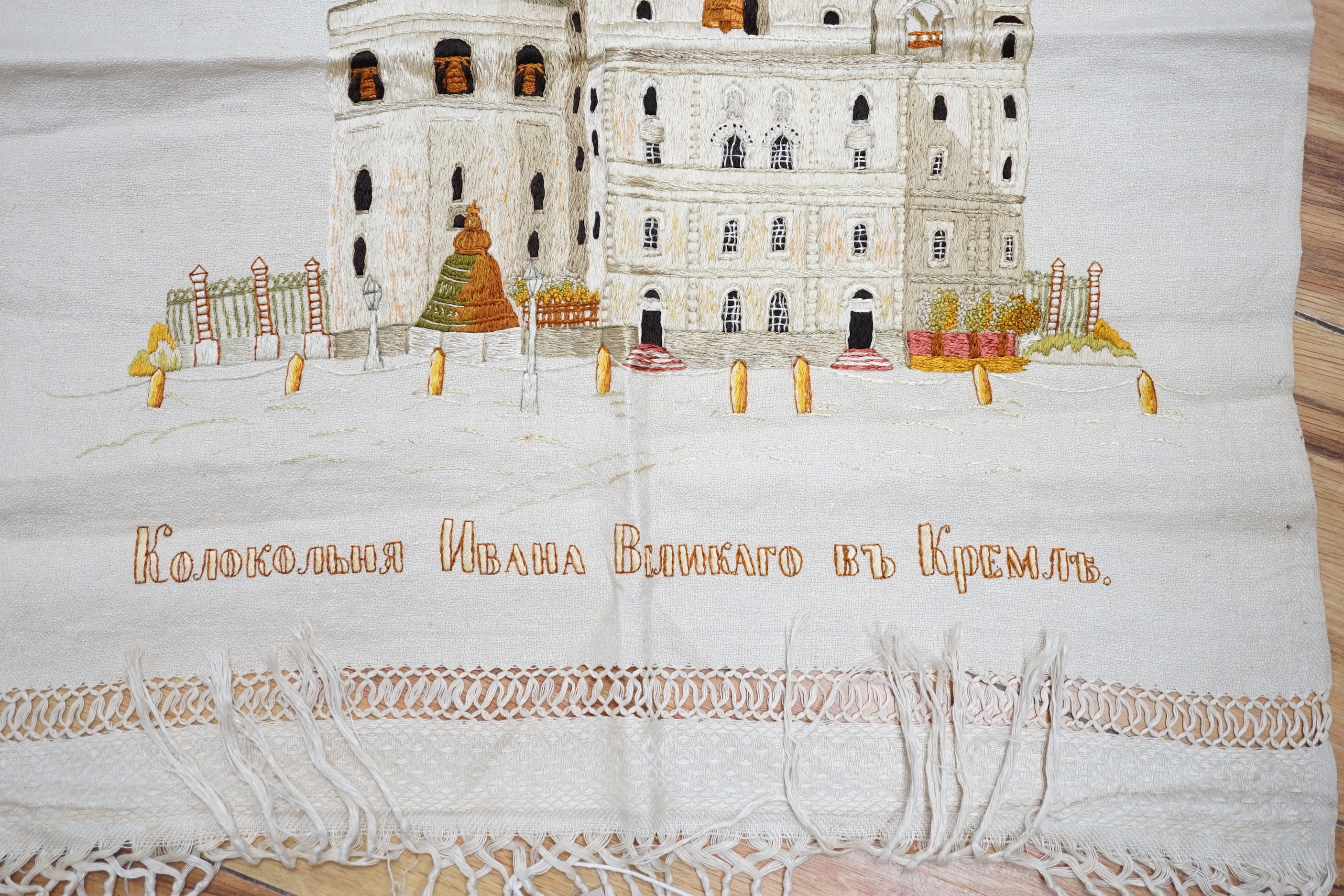 A Russian silk embroidery of a building with embroidered text below: translation ‘Ivan the Greats Belltower, The Kremlin’, 56cm high not including fringe